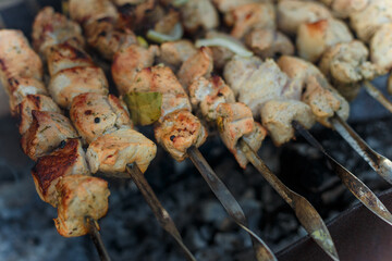 Marinaded pork meat pieces on skewers frying over bonfire. Kebab or traditional shashlik cooking with lot of smoke.