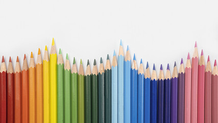 Closeup of colored pencils lined up in a row  and abstract shape on background copy space