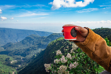 girl holding coffee cup with mountain range and bright blue sky at afternoon from flat angle