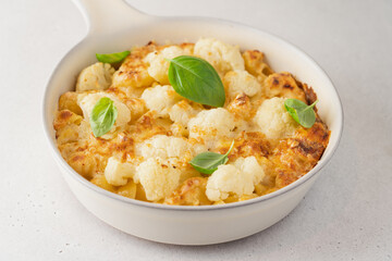 Mac and cheese with cauliflower. Baked pasta with cheese and cabbage in ceramic pot on white background. American cuisine concept