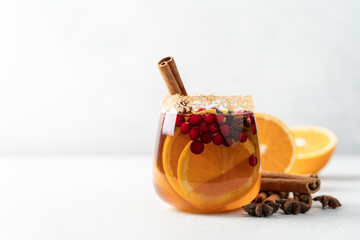 Orange punch with cranberry and spices on white table. Festive Christmas drink. Side view, close-up