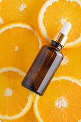 Vitamin C serum in cosmetic transparent bottle with dropper, sliced orange  close-up view. Facial skin care concept. Natural organic cosmetics beauty