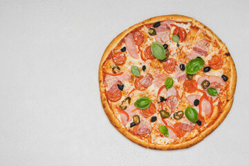 Pizza with salami, pastrami and basil on white table. Top view with copy space