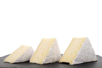 Three fragrant pieces of brie cheese on a slate stone, close-up, isolated on white.