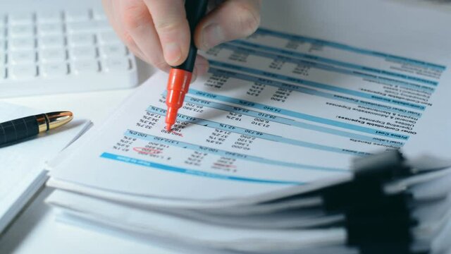 Close-up of ig company boss hands marking data in a business report with a red marker