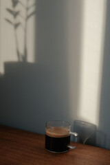 Espresso coffee in glass mug next to Zamioculcas flower on vintage table
