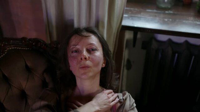 portrait of a brunette in an unbuttoned dress on the sofa. the dark key. top view. the camera is moving