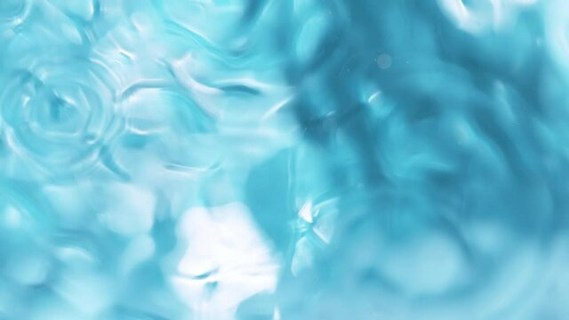 Super slow motion of water surface on light blue background. Filmed on high speed cinema camera, 1000 fps.