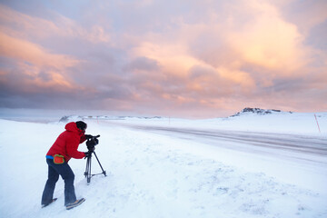 Fototapeta na wymiar Man recording video on the maple of a snowy road