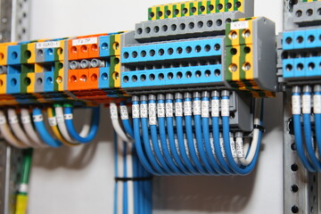 1-level and 3-level electric color terminals with connected white and blue mounting wires located on the din rail. - obrazy, fototapety, plakaty