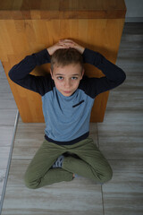 portret młodego chłopaka siedzącego na podłodze  - obrazy, fototapety, plakaty