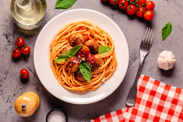 Spaghetti with meatballs and tomato sauce on a stone background