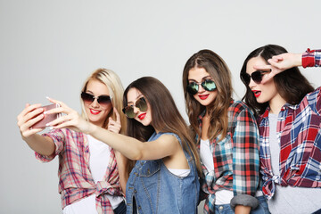 Obraz premium four happy teenage girls with smartphone taking selfie
