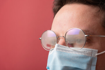 Young man with misted up eyeglasses due to facemask