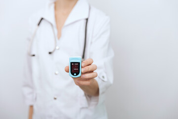 Pulse oximeter with hand of doctor isolated on white. Measuring oxygen saturation, pulse rate and oxygen levels. The concept of portable digital device to measure person's oxygen saturation.