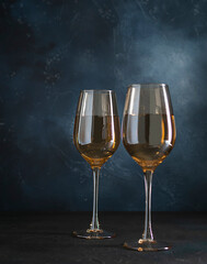 Two transparent glasses with white wine on a dark blue background. Champagne in glass glasses. Dark blue textured background