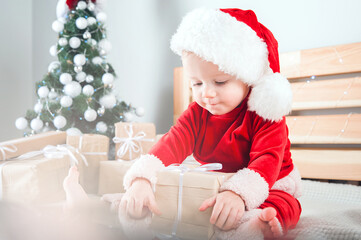 Baby dressed as Santa Claus with Christmas gifts. ..
