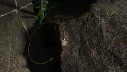 Heart shape Diamond gold bracelet on natural rock with copy space