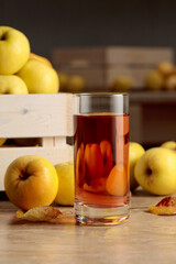 Fresh juicy apples in in wooden box and glass of apple juice.