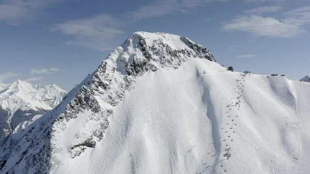Aerial view flight slope ski resort Krasnaya Polyana with snowboarding trace, lift to mount Black Pyramid. Shooting from helicopter amazing winter nature panorama recreational extreme sport center
