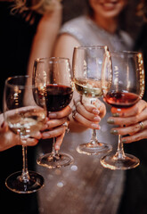Female hands holding a glasses with dark red and white wine. Celebration, holiday, bachelorette party, birthday concept