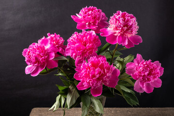 bouquet of pink peonies in a vase on a dark background