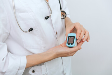 Pulse oximeter with hand of doctor isolated on white. Measuring oxygen saturation, pulse rate and oxygen levels. The concept of portable digital device to measure person's oxygen saturation.