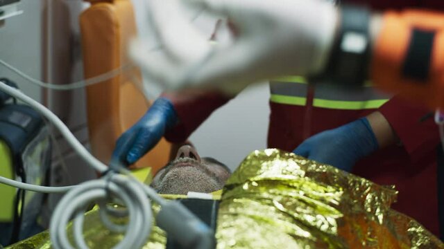 Unrecognizable doctors preparing to reanimate senior survivor inside emergency vehicle during rescue mission