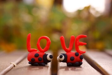 Naklejka premium A pair of ladybugs and the inscription love close-up. The figures look at each other.