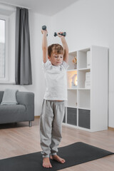 Fototapeta na wymiar Healthy lifestyle. Portrait of a boy exercising with dumbbells at home in the living room.