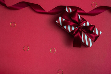 Striped gift box with a red bow on a colored background. Closeup monochrome.