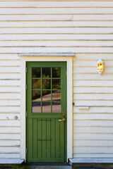 Green wooden door on white wooden house