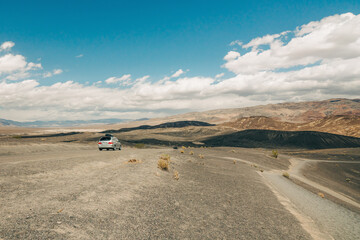 Fototapeta na wymiar Death Valley National Park road trip. Desert landscape and one car on an unpaved road
