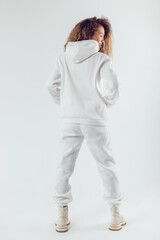 Woman with thick curly hair in a white suit from a hoodie and sweatpants back view.