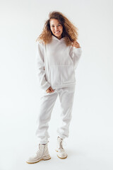 Smiling woman with thick curly hair in a white suit of hoodies and sweatpants.