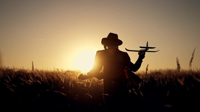 Happy girl with oy in natural park. Child runs on grass with an airplane. Chidhood dream. Happy baby girl with toy airplane at sunset. Child runs on grass in field. Dream travel concept