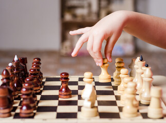 Child, preschooler, enthusiastically plays wooden chess