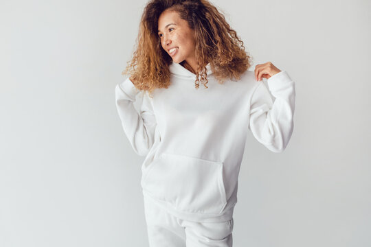 Attractive woman with thick curly hair in a white suit of hoodies and sweatpants. Mock-up.