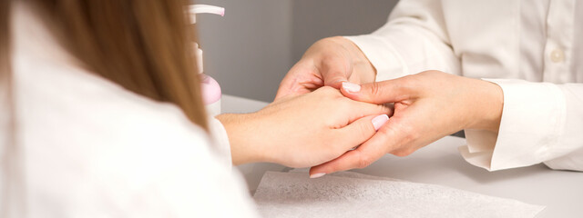 Fototapeta na wymiar Manicure master massaging female hands before nail procedure in a nail salon