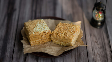 two pieces of cake on a plate with parchment. Honey cake and napoleon cake. Homemade baking.