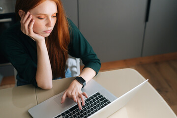 High-angle view of tired young woman office worker unmotivated and disinterested in dull work with laptop. Lazy female freelancer feeling lack of motivation, annoyed with boredom and boring job.