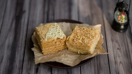 two pieces of cake on a plate with parchment. Honey cake and napoleon cake. Homemade baking.