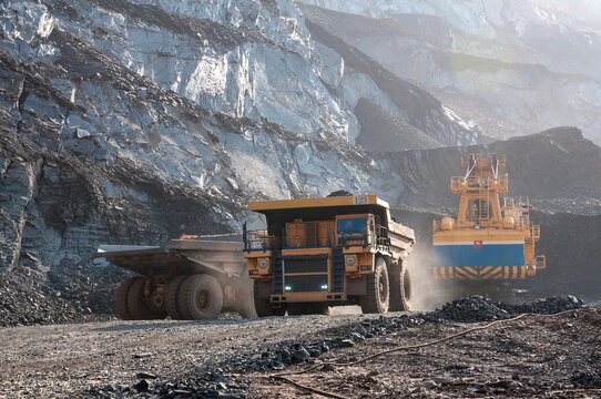 open cast mine dump trucks drive alone industrial area of iron ore quarry