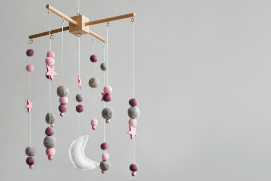 Baby crib mobile with stars, planets and moon. Kids handmade toys above the newborn crib. First baby eco-friendly toys made from felt and wood. Space for text.