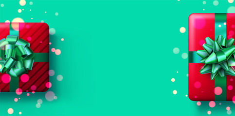 Christmas red gift box on green background with confetti and bokeh.