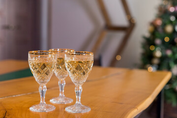 Corporate party: sparkling champagne glasses on wooden table.New Year picture of three glasses with wine on christmas tree background