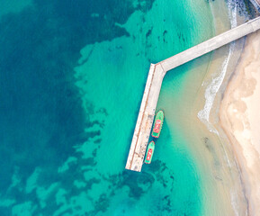 Wooden dock and two boats with blue sea. Aerial drone view of beautiful sea and beach. Summer holiday background view.