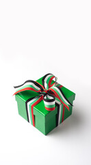 A paper gift box wrapped with UAE flag color ribbon shot on white background. UAE national day celebration elements and objects.