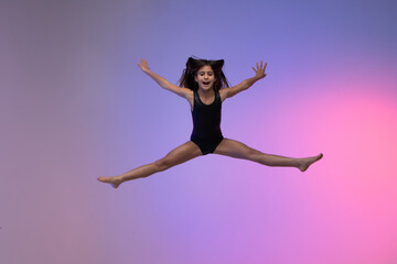 young gymnast athlete performing acrobatic jumps, training for competition, looking at photo, colorful background in a studio