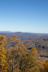 autumn landscape in the mountains. vertical photo of a yellow tree with blue sky and lake at the background